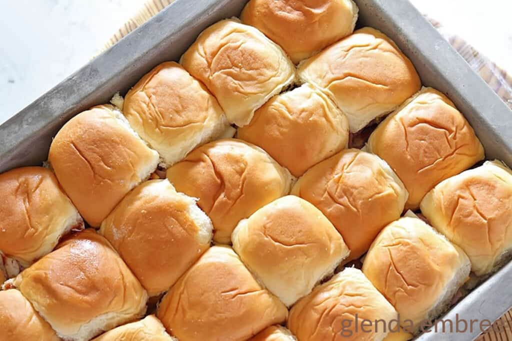 ham and cheese sliders in a silver 9x13 baking pan sliders ready to be glazed