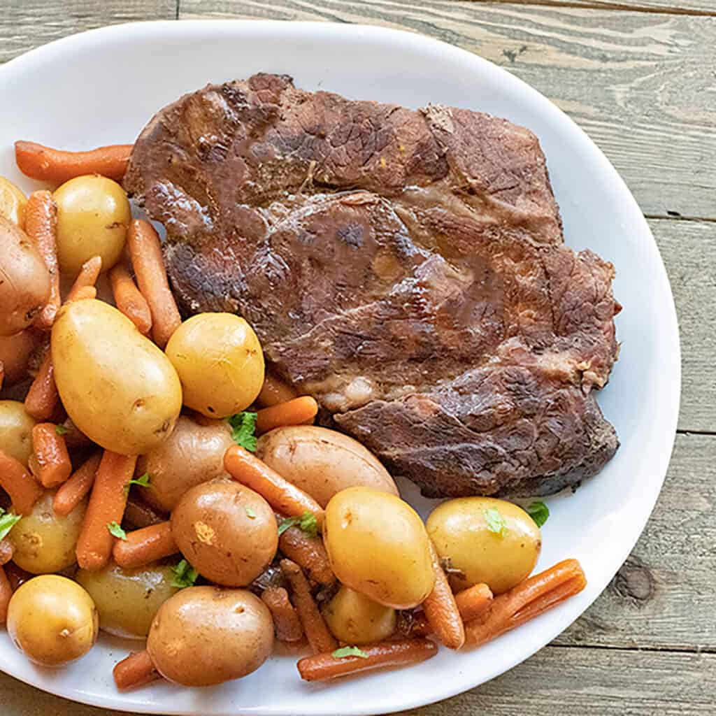 roast with potatoes and carrots on a white platter
