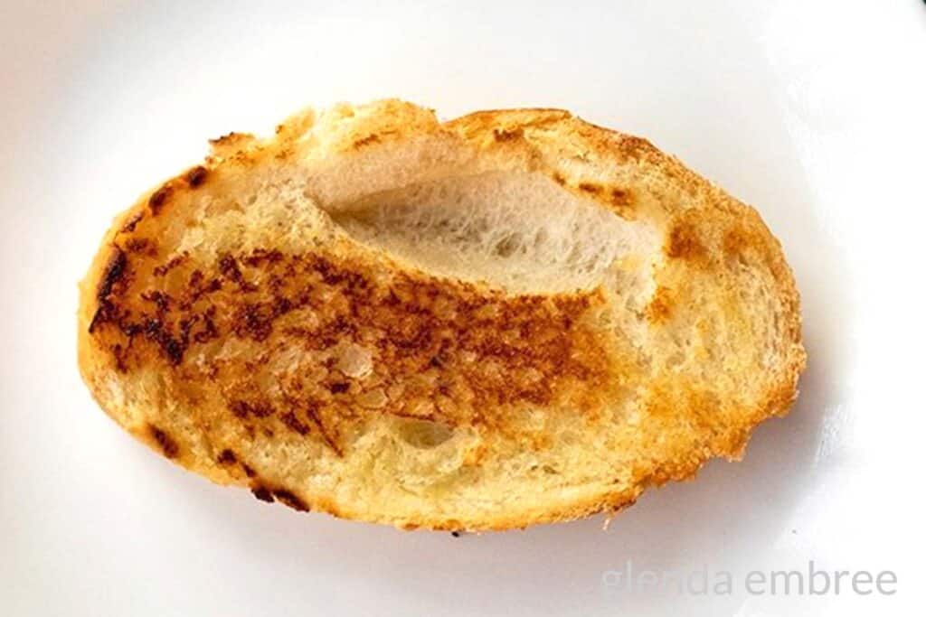 toasted slice of French bread on a white plate.