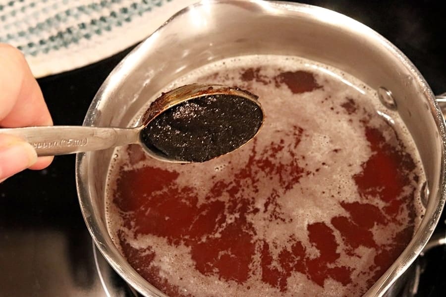 adding beef base to beef broth in a saucepan