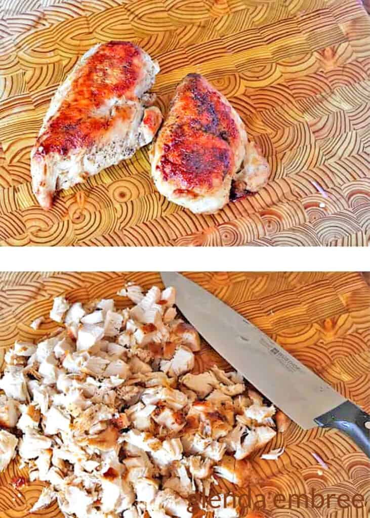 cooked chicken breast on a wooden cutting board being chopped for soup