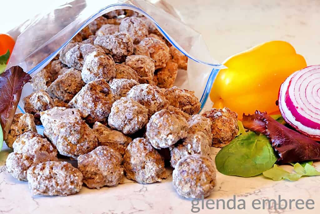 homemade meatballs frozen in a zip top bag whick is sitting on a marble countertop