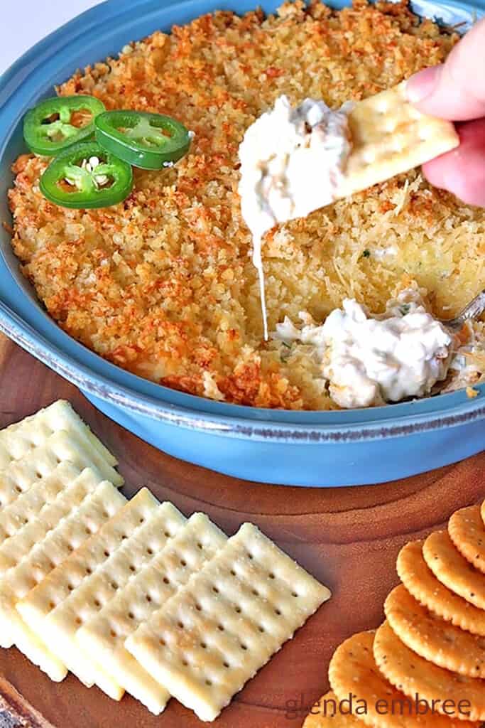 hot jalapeno popper dip in a blue stoneware baking dish served with crackers