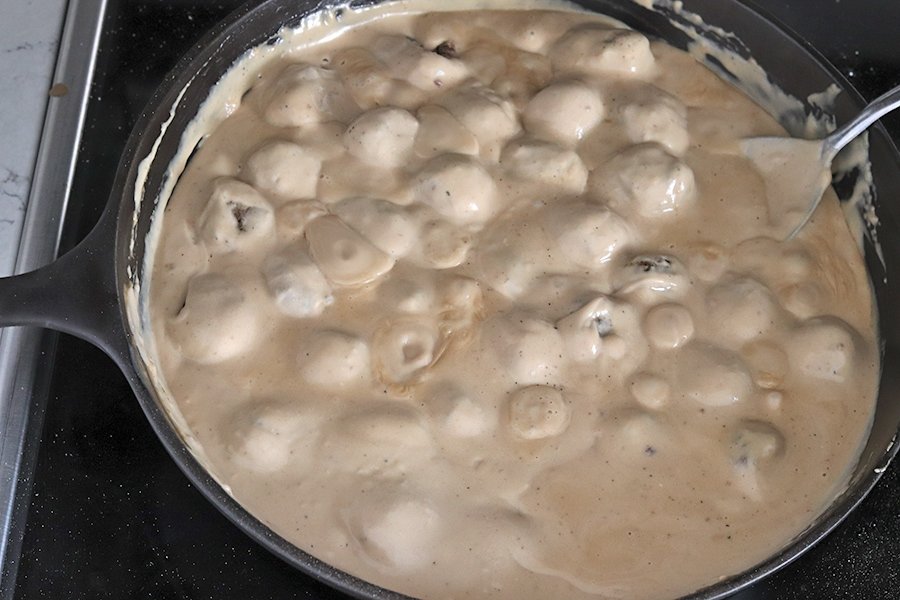 Meatballs in brown gravy warming in a cast iron skillet  - meatballs in brown gravy - Swedish meatballs