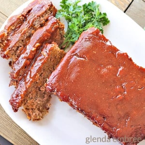 easy meatloaf served and sliced on a white platter with parsley garnish