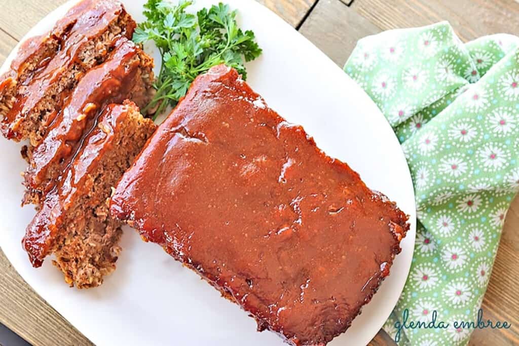 easy meatloaf served and sliced on a white platter with parsley garnish
