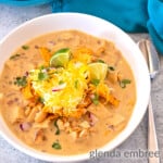 creamy white chicken chili in a white ceramic bowl on a concrete countertop with a turquoise cloth napkin to the right of the bowl