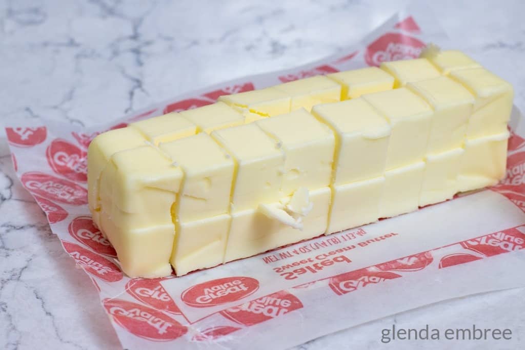 Butter cubed and sitting on a butter wrapper