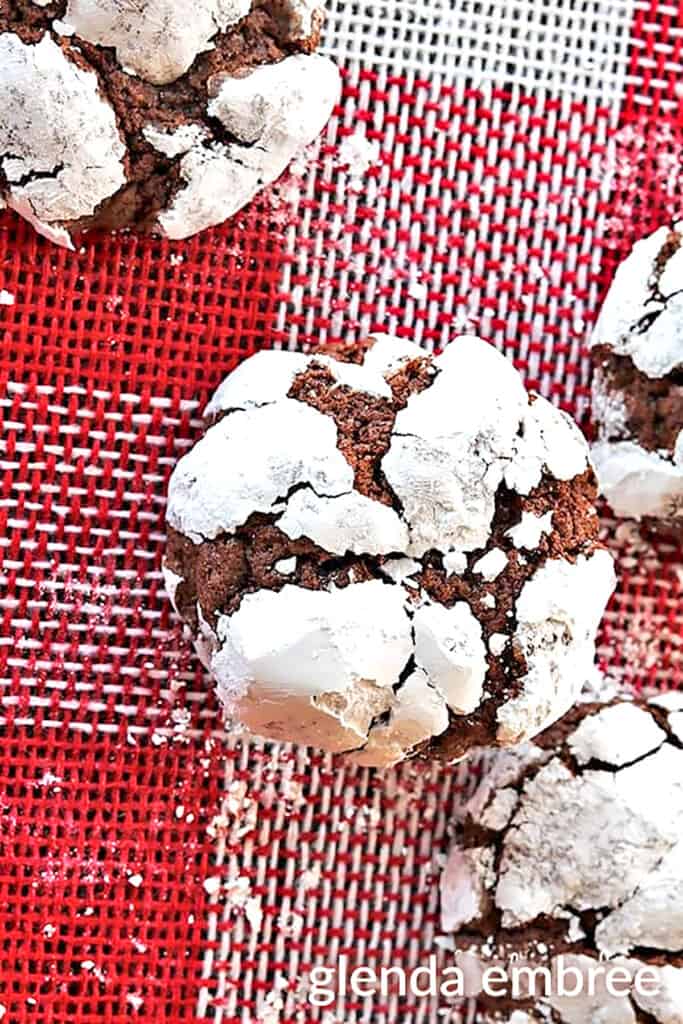 Chocolate Crinkle Cookies on two pieces of Christmas burlap one is red and white checks, the other brown with red snowflakes