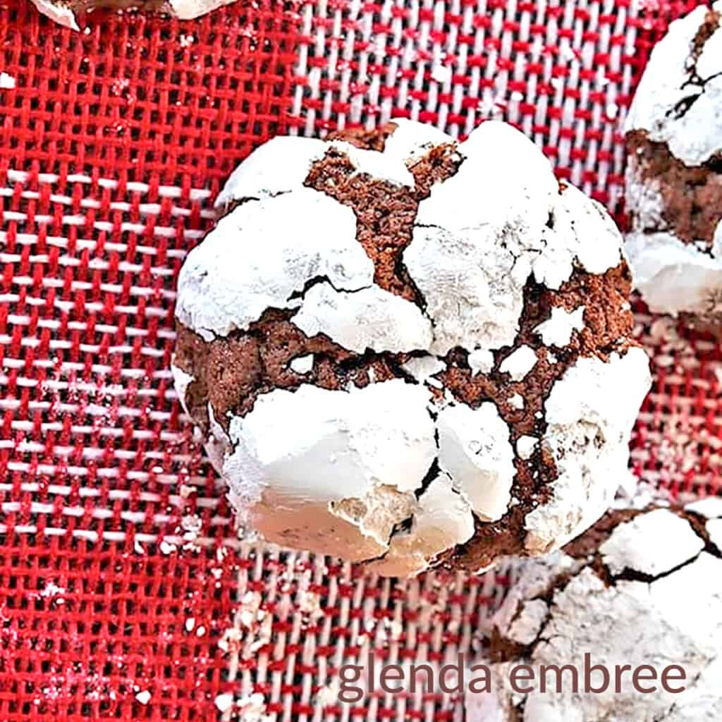 Chocolate Crinkle Cookies on two pieces of Christmas burlap one is red and white checks, the other brown with red snowflakes