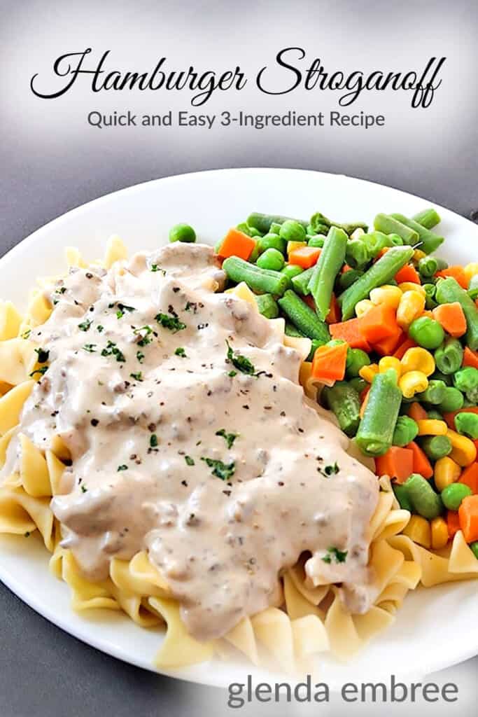 Hamburger Stroganoff over egg noodles served on a white plate with mixed vegetables