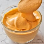 Cheesy Hot Sauce Dip in a clear bowl on a marble counter