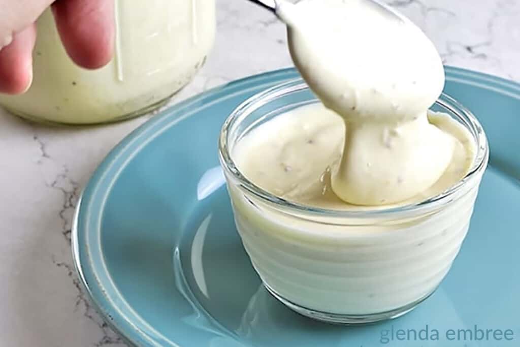 easy homemade mayonnaise in a clear glass bowl sitting on a blue plate