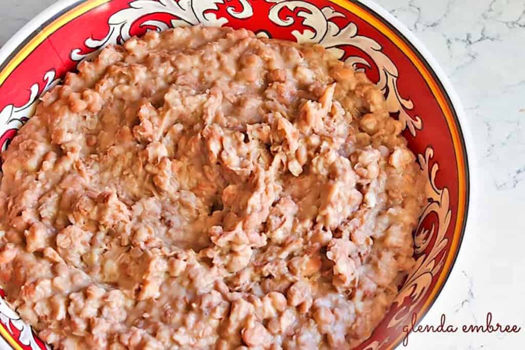 Homemade Refried Beans in a red and white serving bowl