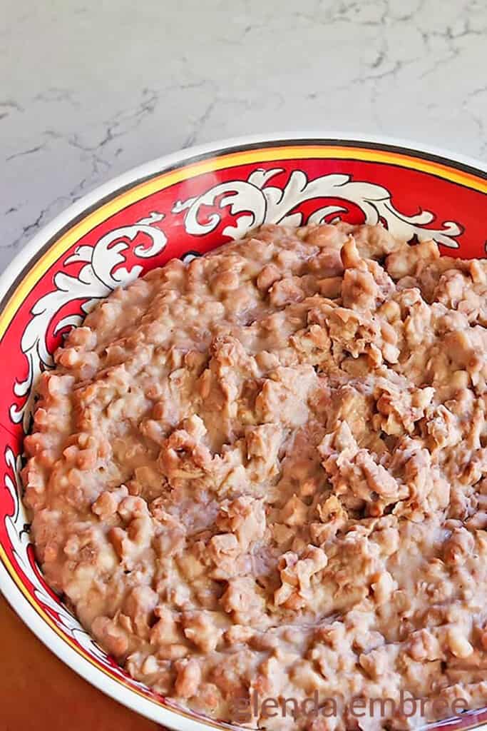 Homemade Refried Beans in a red and white serving bowl