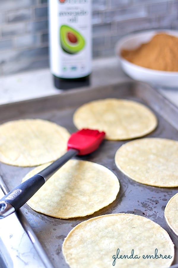 Brushing corn tortillas with oil to make taco chips.