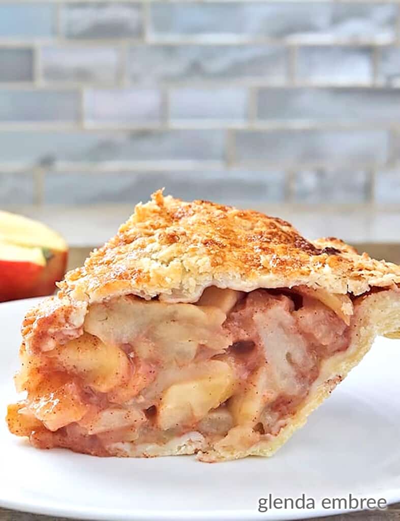 homemade apple pie with buttery flaky pie crust served on a white plate