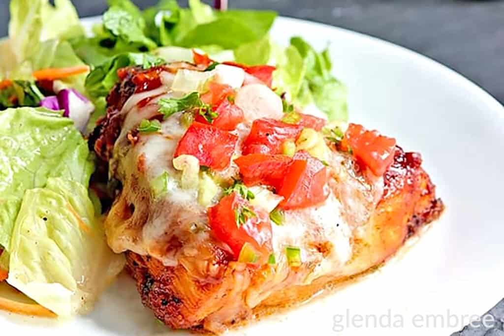 Monterey Chicken served on a white plate with house salad.