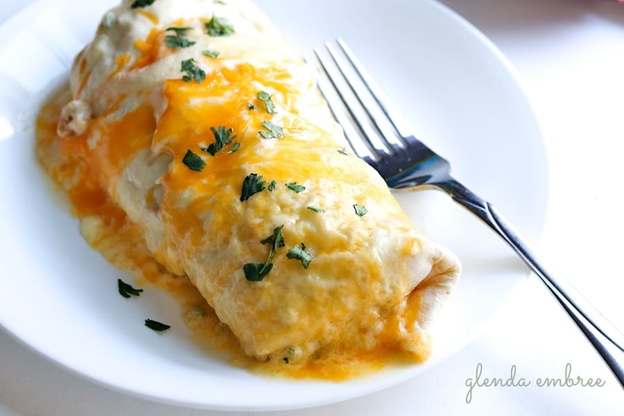 creamy chicken enchiladas sprinkled with chopped cilantro served on a white plate
