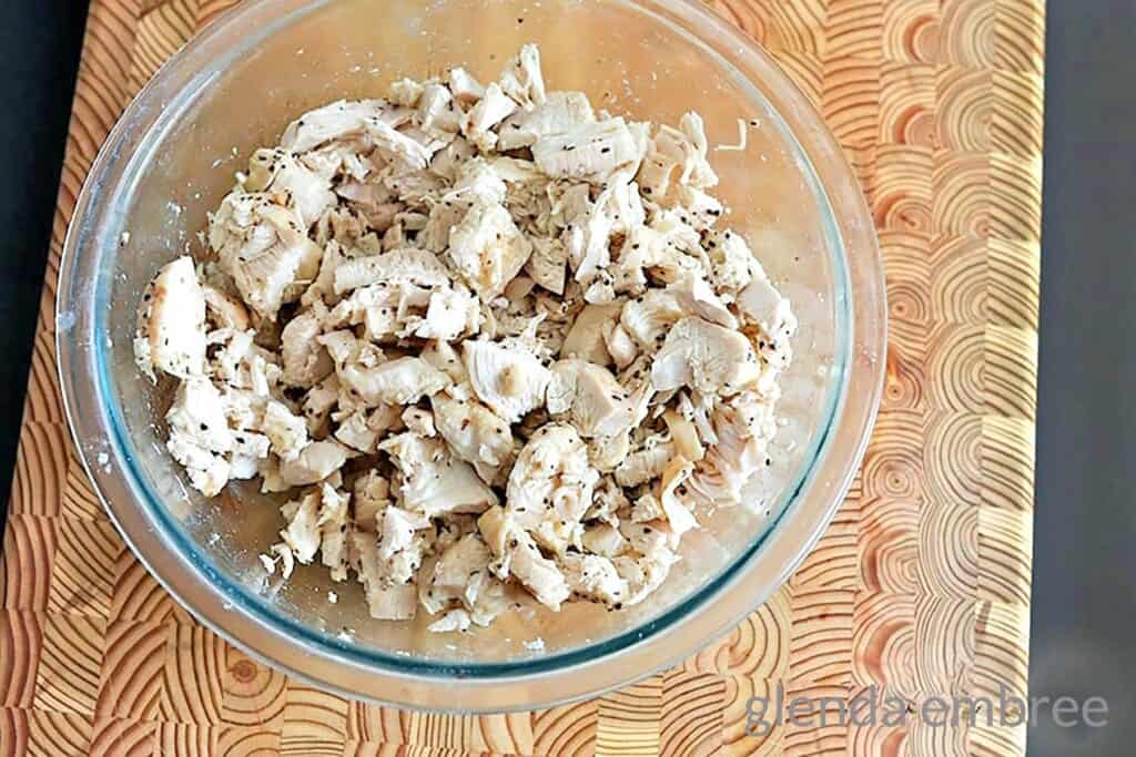 Clear bowl of pre-cooked, chopped chicken breast.