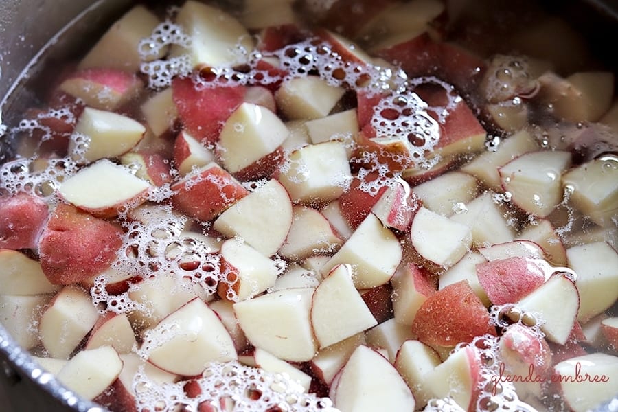 cut red potatoes boiling in a pan