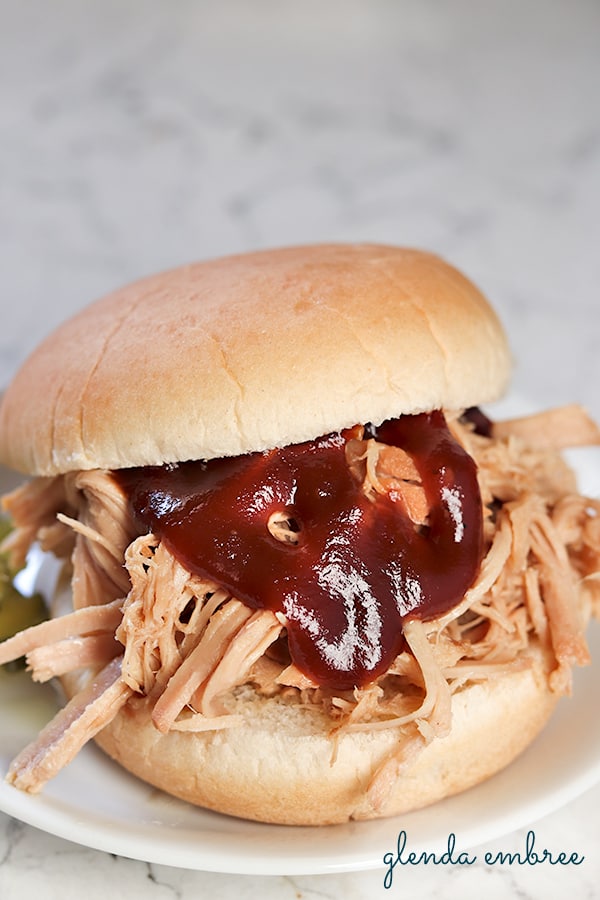 Pulled Pork Sandwich with bbq sauce on a white plate.