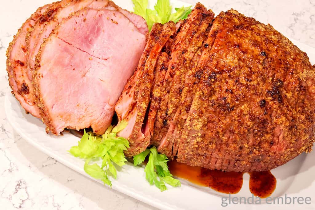 crock pot ham on a white platter sliced for serving