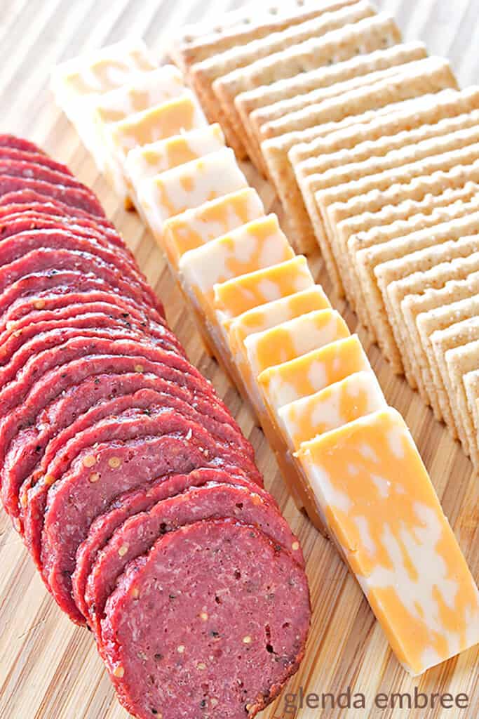 homemade summer sausage on a wooden board with cheese and crackers