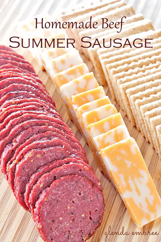 homemade summer sausage on a wooden board with cheese and crackers