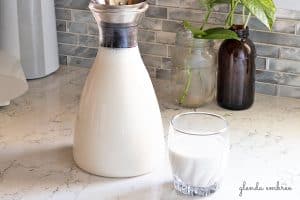 Cashew Coconut Milk in a glass bottle with a glass of Cashew Coconut Milk on the side. Fabulous dairy alternative and non-dairy blend.