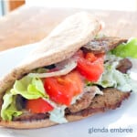 gyro sandwich with homemade gyro meat tomatoes onions lettuce and tzatziki in a whole grain pita