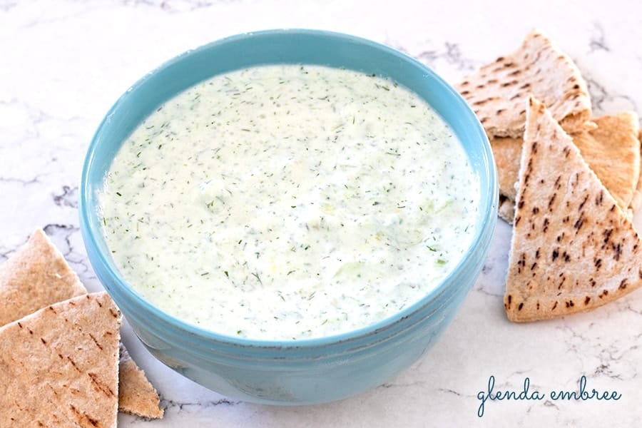 homemade tzatziki sauce in a blue bowl with pita chips