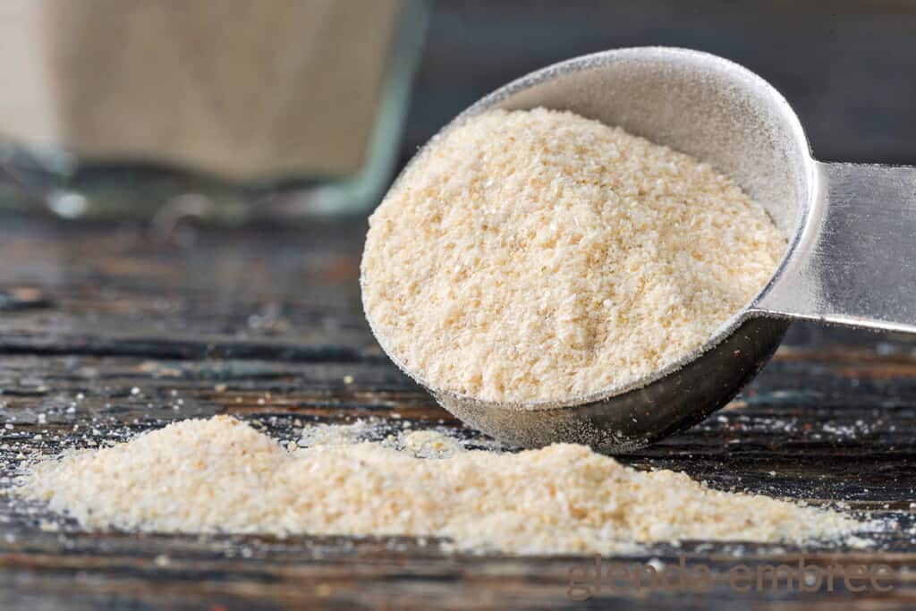 Tablespoon of onion powder tipped and spilling onto a wooden table