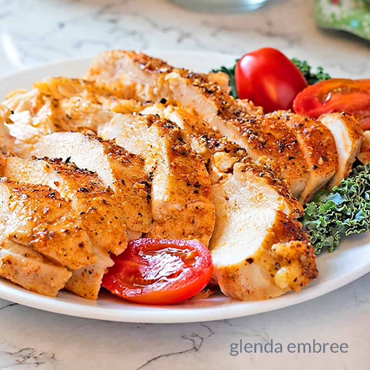 Perfect Baked Chicken Breasts on a platter with kale and tomato garnish  - easy recipes - family recipes