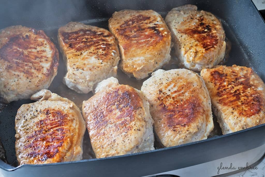 Perfect Pan Seared Pork Chops cooking in an electric skillet