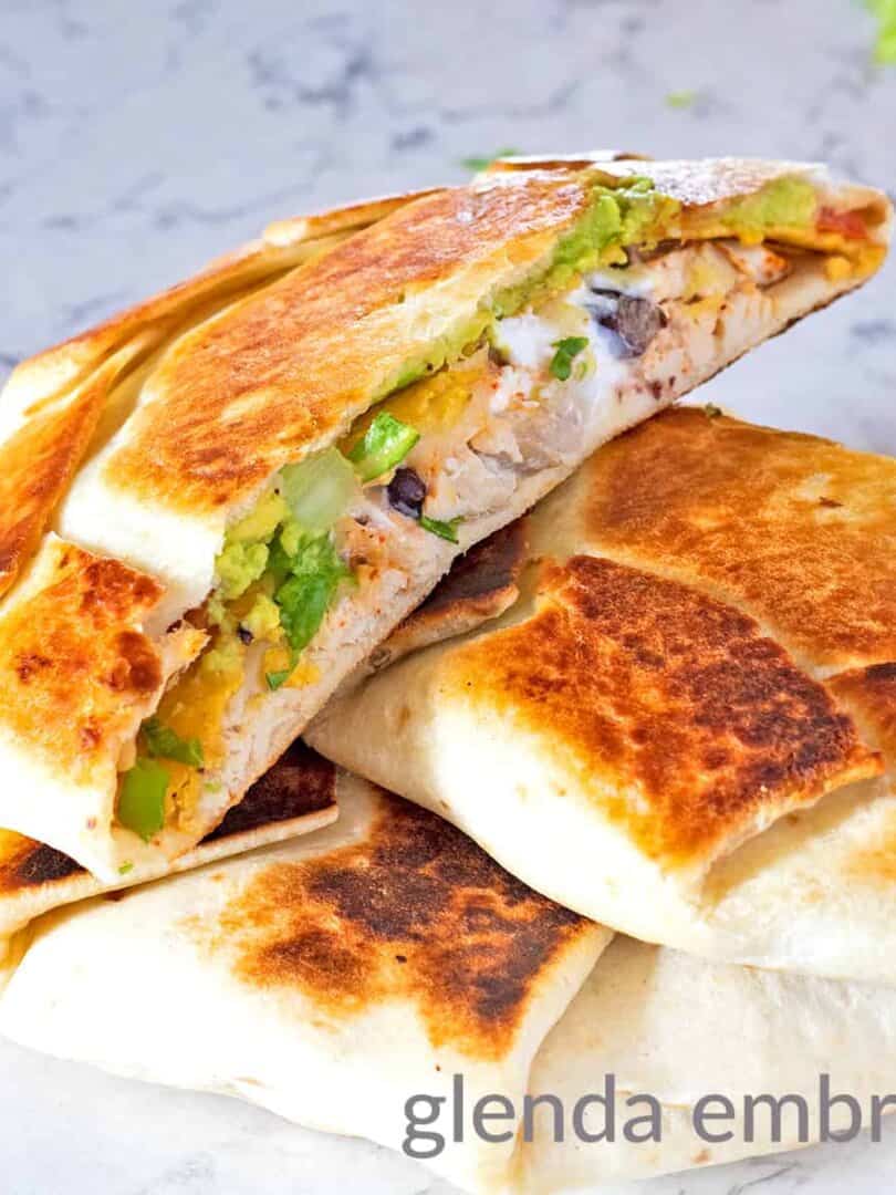 Chicken Crunch wrap supreme cut in half and resting on a marble counter