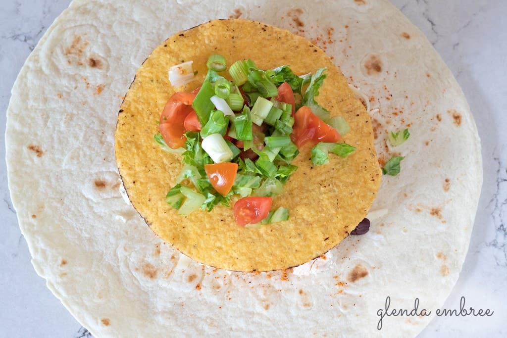 How to Assemble a Crunch Wrap: Add tomatoes and green onion