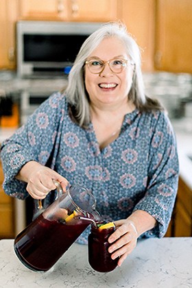 Glenda Embree, from glendaembree.com, pouring blueberry lemonade in her own kitchen.