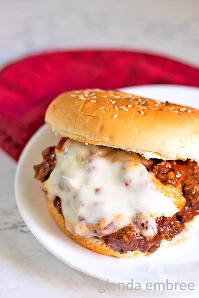 Easy Homemade Sloppy Joes with cheese on a white plate.  A red pot holder is in the background.