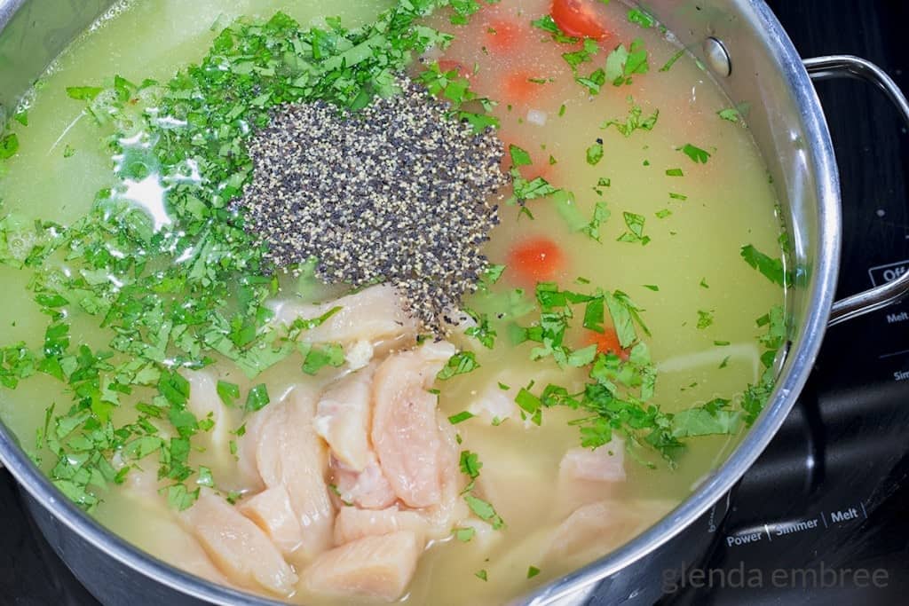 adding chicken broth, lime juice and black pepper to the stock pot for making Avocado Lime Chicken Soup