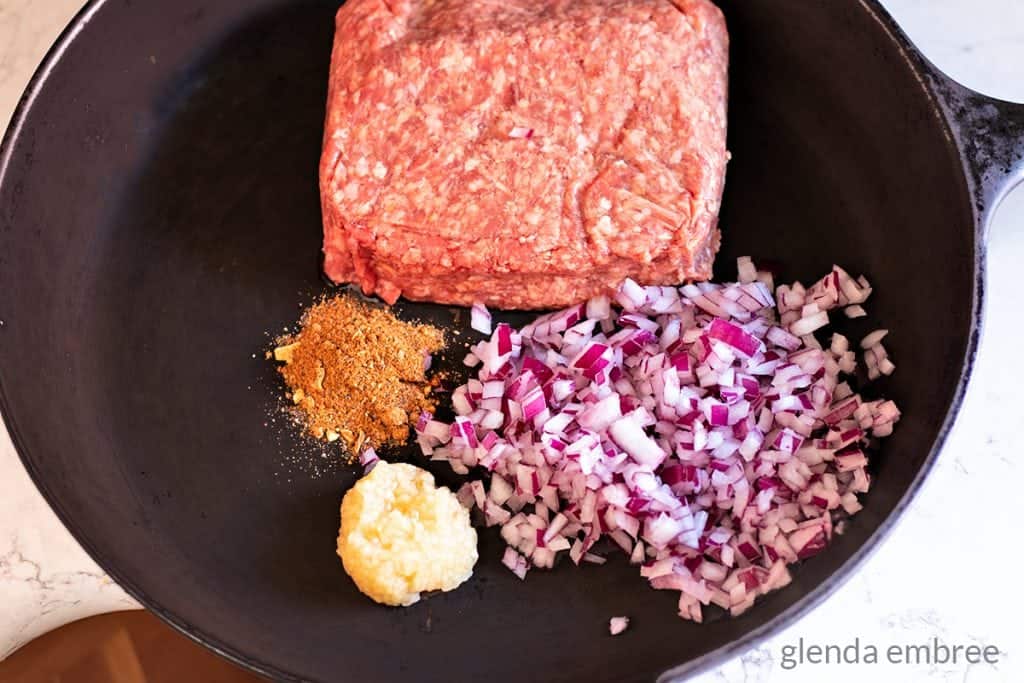 Ground beef, minced red onion, minced garlic and all purpose seasoning in a cast iron skillet.