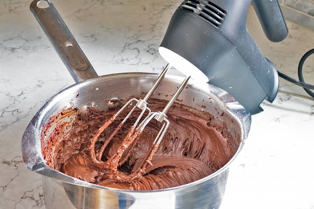 hand mixer in a saucepan beating chocolate frosting