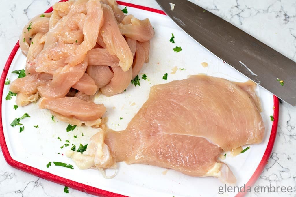 chicken breasts being cut into thin strips