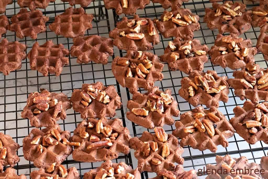 turtle cookies on a cooling rack with pecans on top
