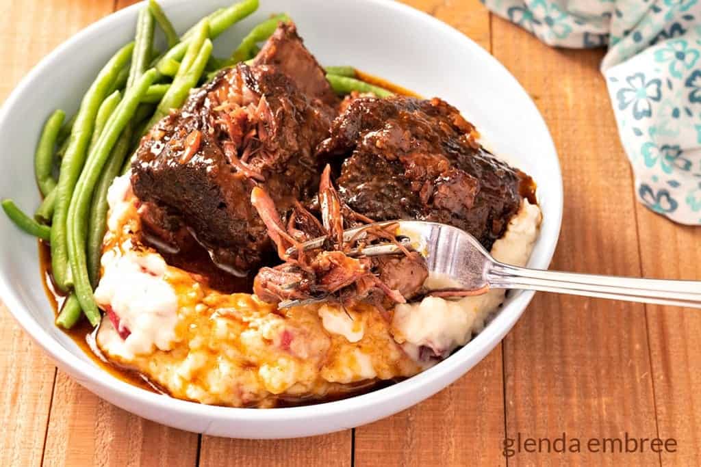 Braised Beef Short Ribs on a bed of garlic mashed potatoes with green beans on the side