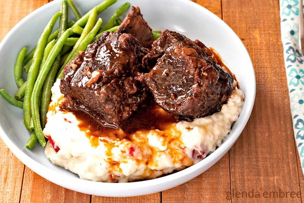 Braised Beef Short Ribs on a bed of garlic mashed potatoes with green beans on the side