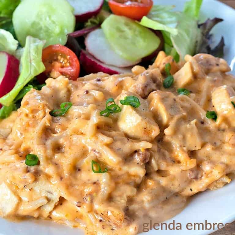 Cheesy Chicken Spaghetti served on a white plate with a green salad and veggies