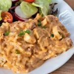 Cheesy Chicken Spaghetti served on a white plate with a green salad and veggies