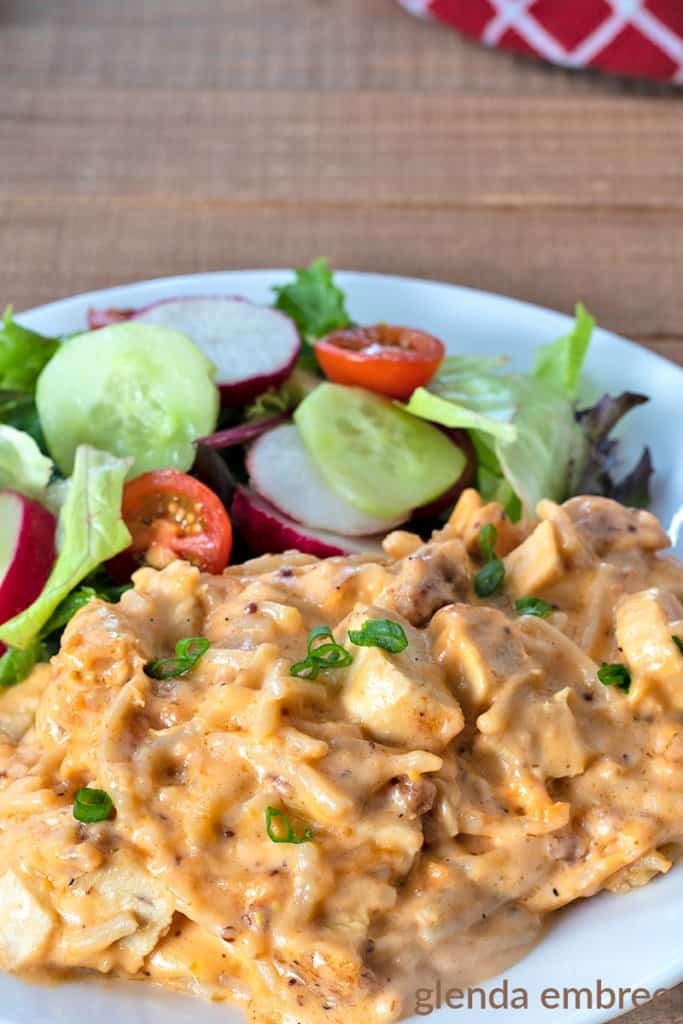 Cheesy Chicken Spaghetti served on a white plate with a green salad and veggies