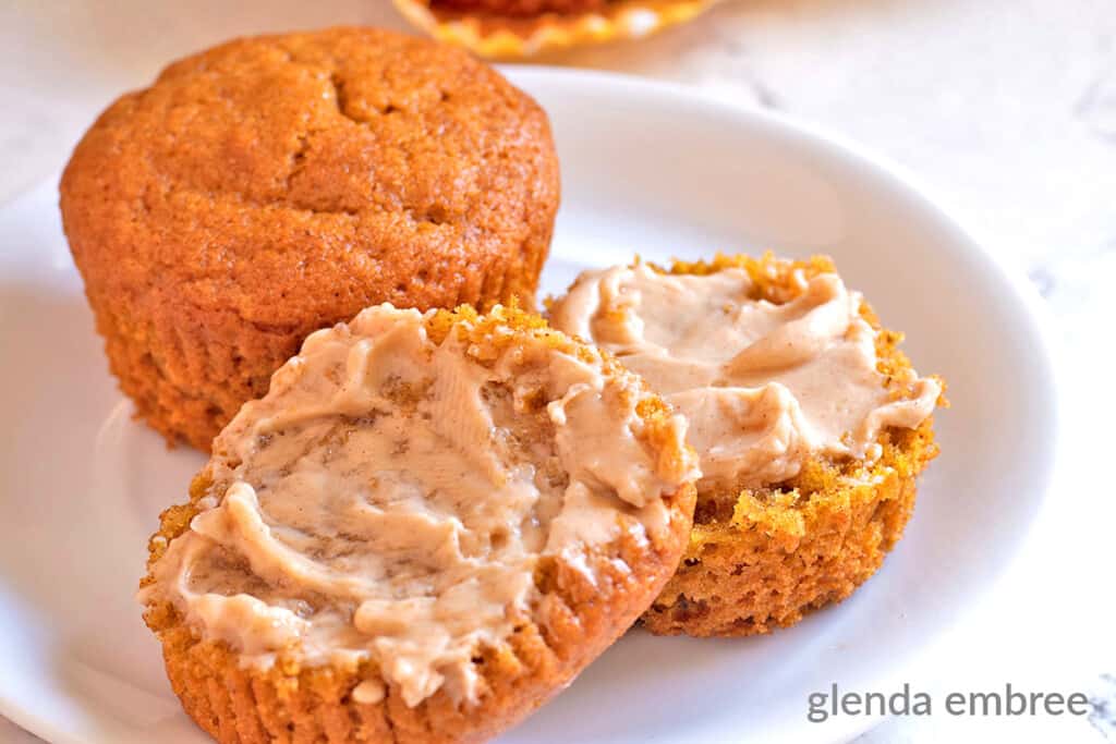 Gluten Free Pumpkin Muffins slathered with Maple Butter and sitting on a white plate.